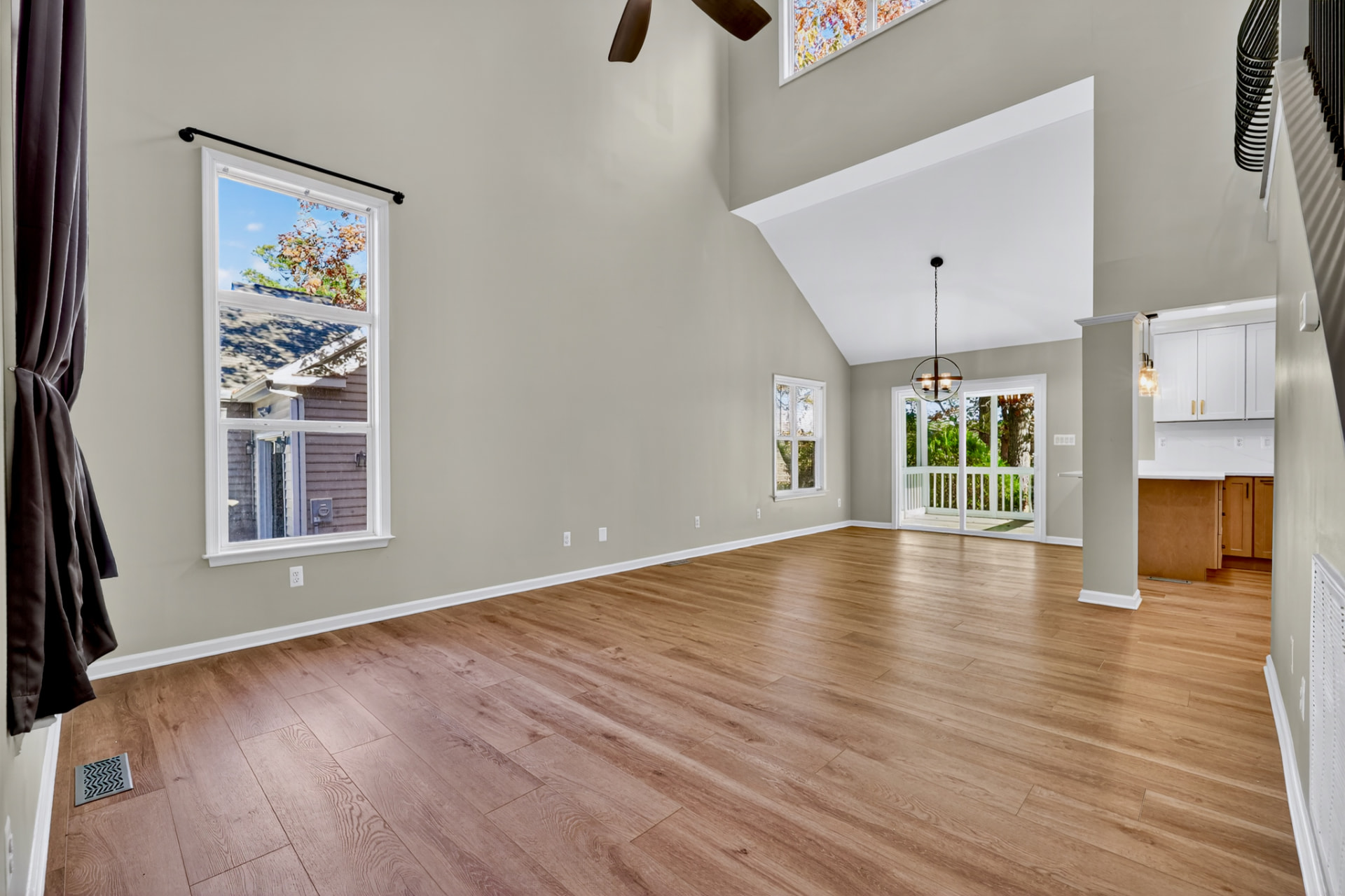 Empty unfurnished great room with vaulted ceiling and hardwood floors