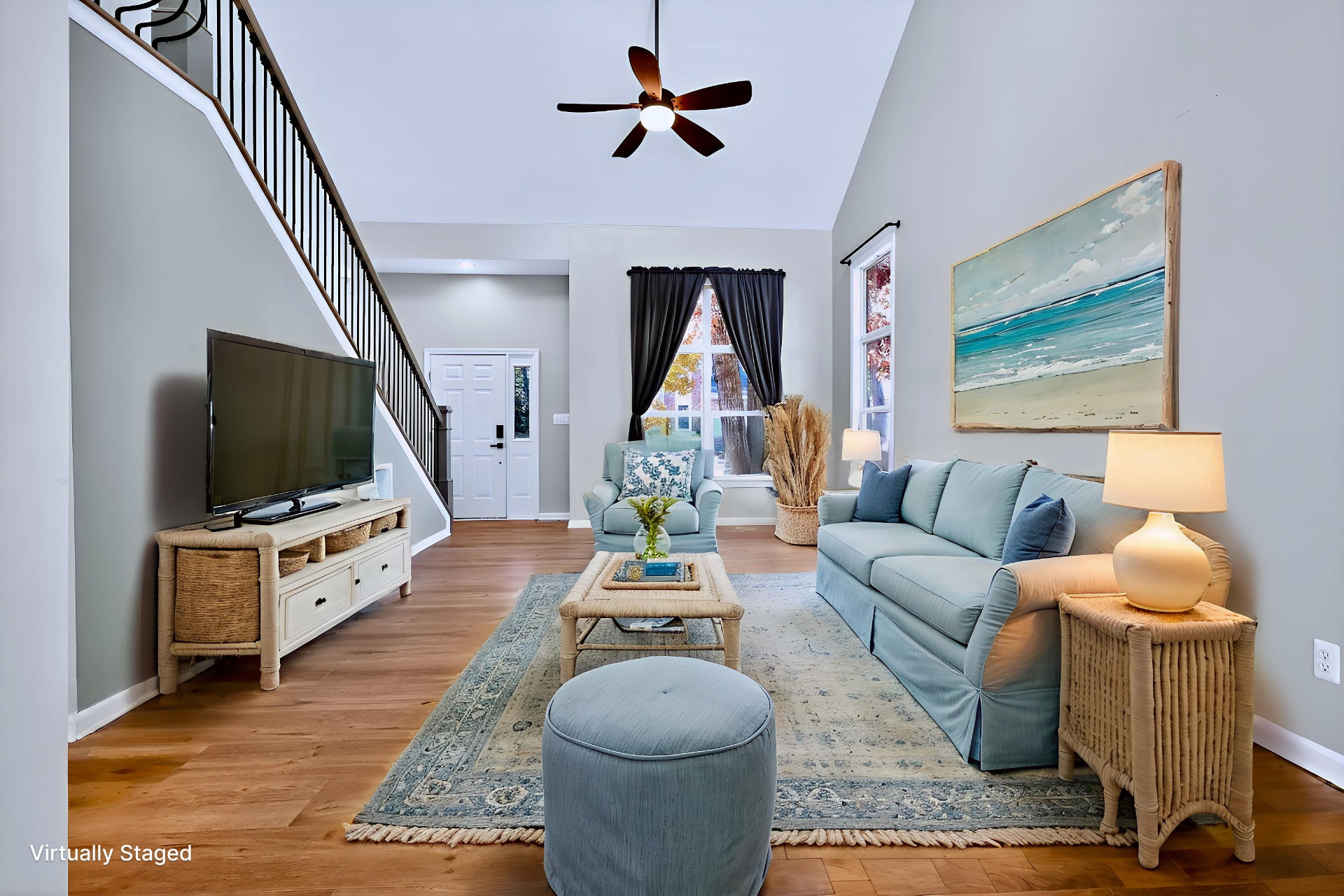 The same great room restaged virtually with a light blue sofa and coastal decor